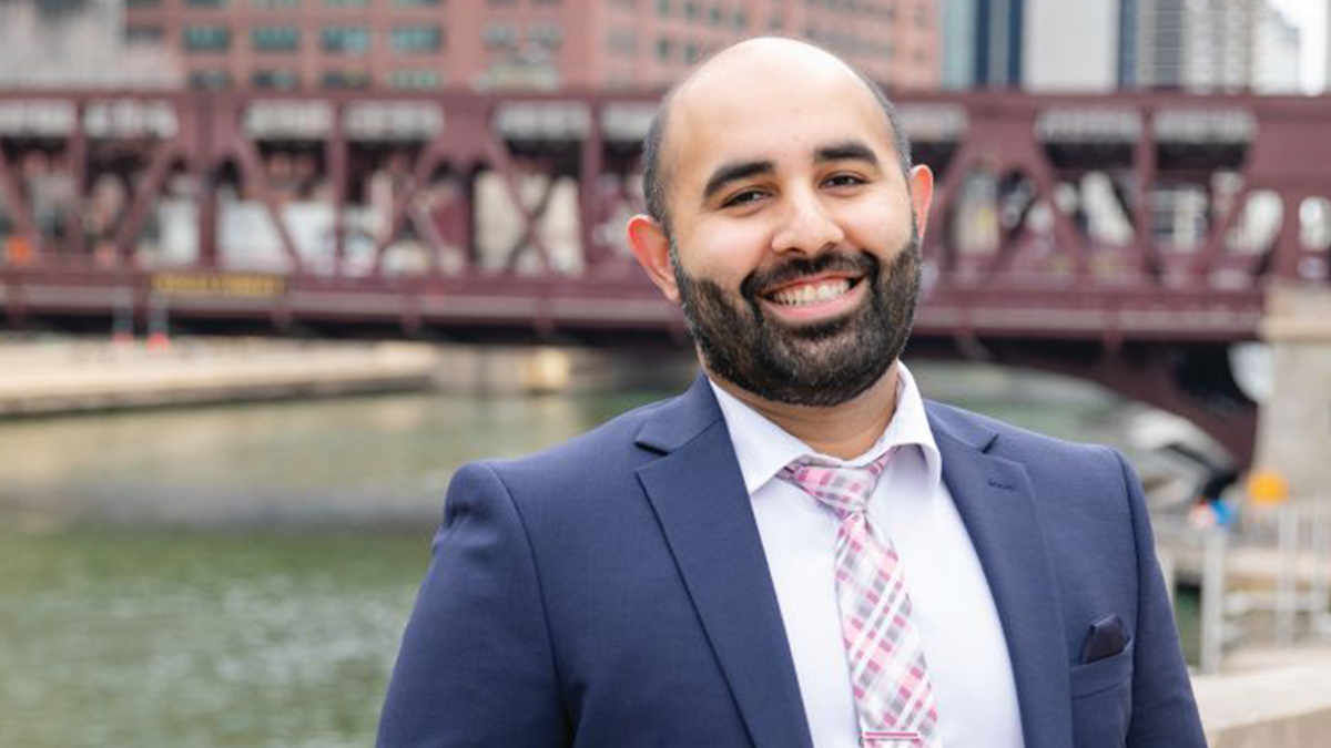 Dr. Jadeep Mann, who found his job on PracticeLink, smiling, standing in front of a bridge